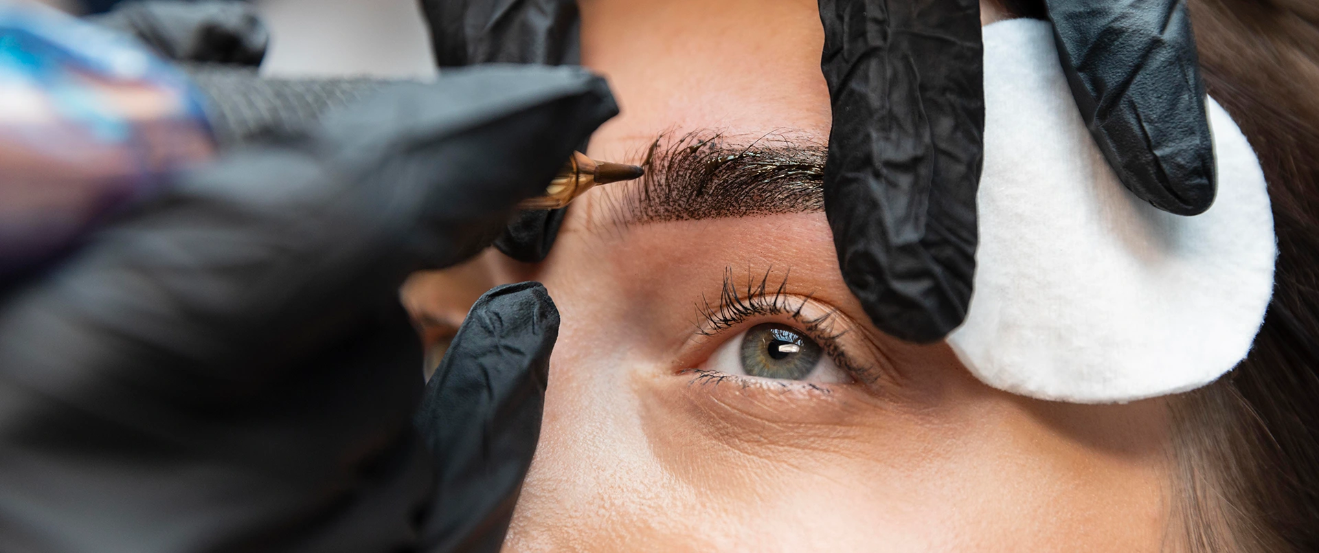 Eine Kosmetikerin tätowiert einer Kundin Powder Brows.